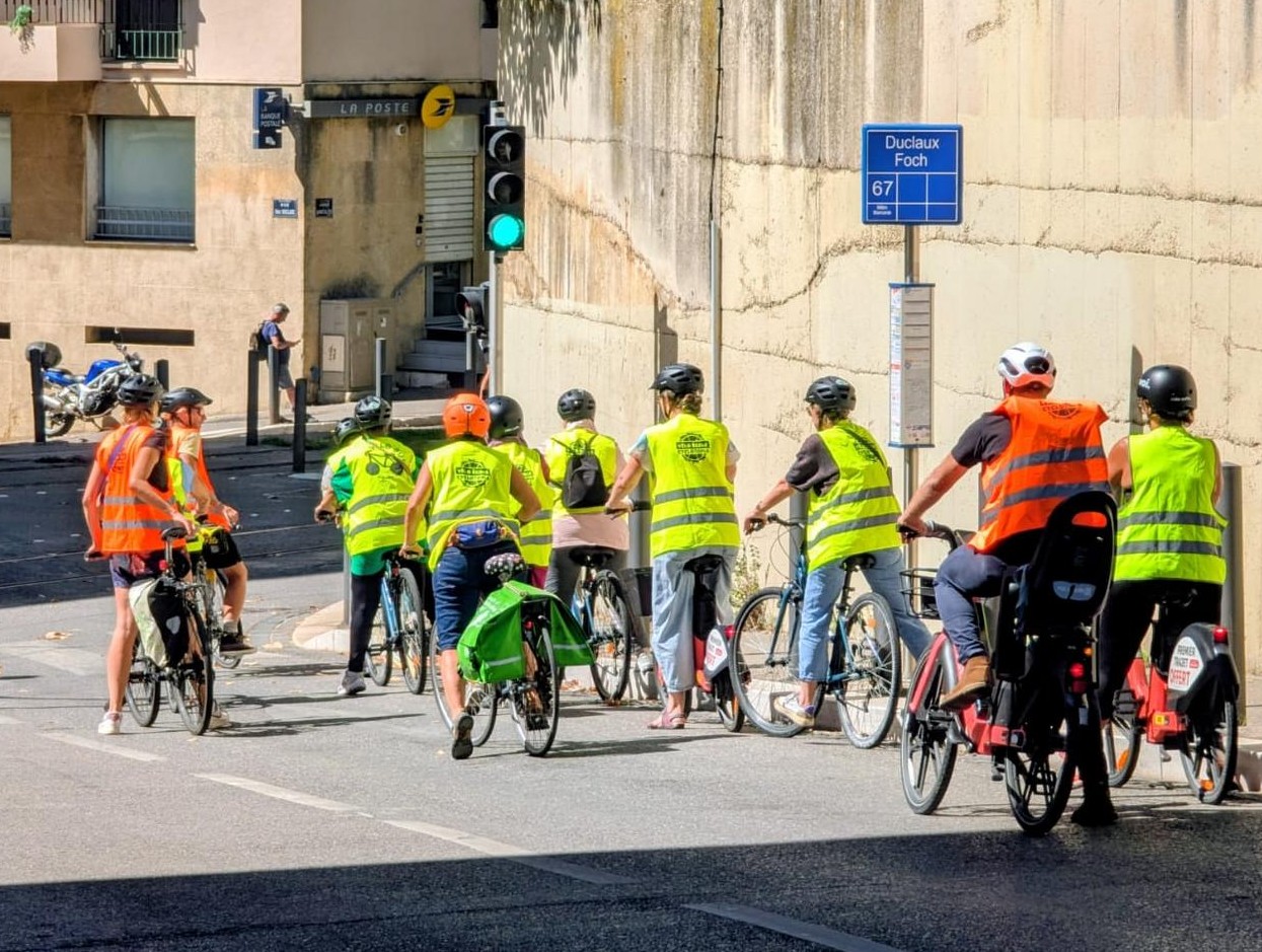 Image 2 : Groupe de cyclistes portant des gilets de sécurité à un feu rouge dans une rue de Marseille.